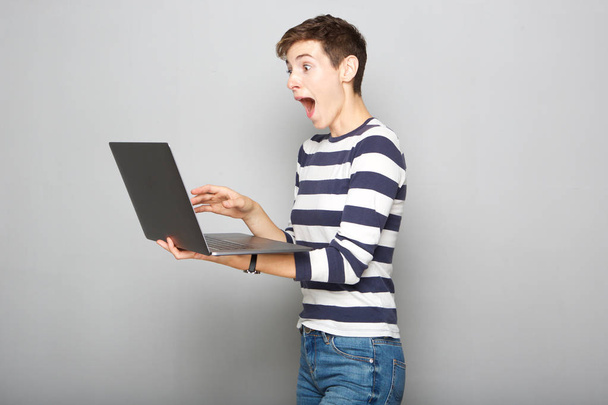 Portrait de jeune femme heureuse tenant ordinateur portable avec expression surprise
 - Photo, image