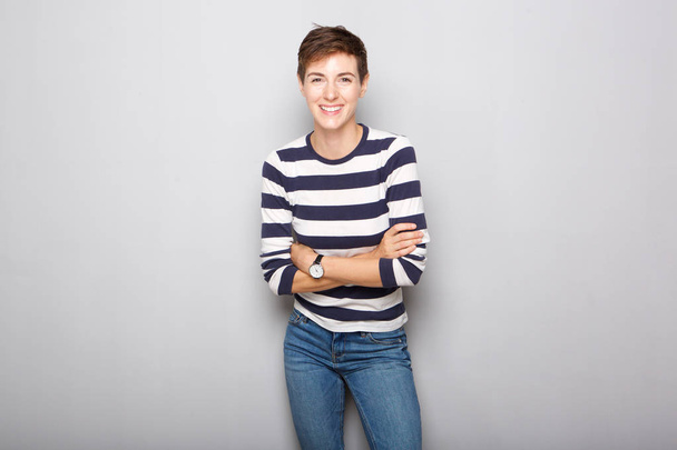 Portrait of smiling young woman with short hair against gray background - Photo, Image