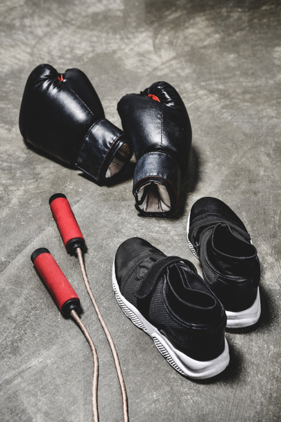 sneakers with jumping rope and boxing gloves on concrete surface - Фото, изображение