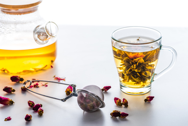 cup of chinese flowering tea, teapot and tea strainer with dried rose buds - Photo, Image