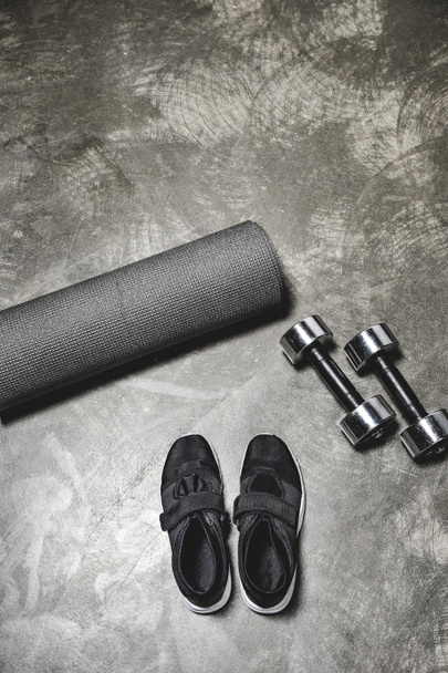 top view of sneakers with yoga mat and dumbbells lying on concrete surface - Photo, Image