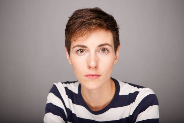Close up portrait of serious young woman with short hair staring - 写真・画像