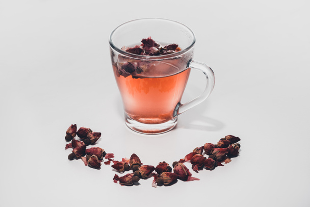 gedroogd rose toppen thee in beker op wit tafelblad - Foto, afbeelding