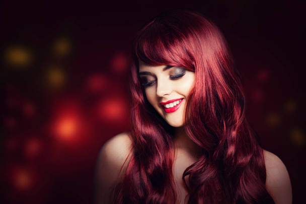 Vöröshajú nő, hosszú vörös göndör frizura. Mosolygó divat-model, csillogó party háttér - Fotó, kép