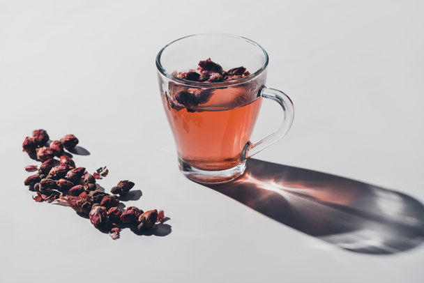 red tea of dried roses in cup on white tabletop - Fotó, kép