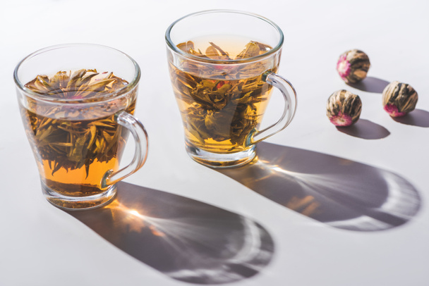 δύο φλιτζάνια, κινέζικο ανθοφορία τσάι με τσάι μπάλες στο τραπέζι - Φωτογραφία, εικόνα