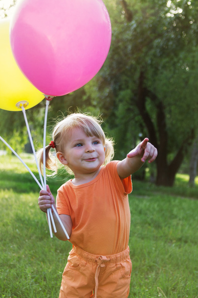 Happy baby girl with balloons among meadow - Φωτογραφία, εικόνα