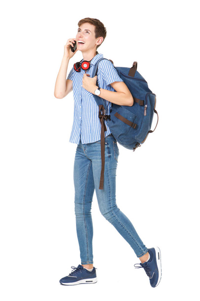 Full body portrait of young woman walking and talking with mobile phone and bag on isolated white background - 写真・画像