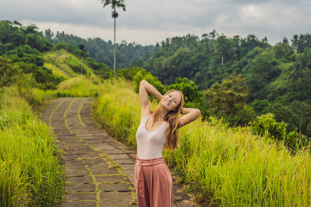 Young woman posing with raised arms behind head and smiling, Campuhan Ridge Walk, Scenic Green Valley, Ubud, Bali. - Foto, imagen