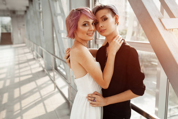 people, homosexuality, same-sex marriage, travel and gay love concept - close up of happy women couple hugging over metall bridge. Two girlfriend walking. - Фото, изображение
