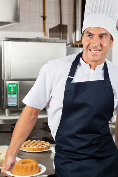 Male Chef Holding Baked Cake In Kitchen - Foto, immagini