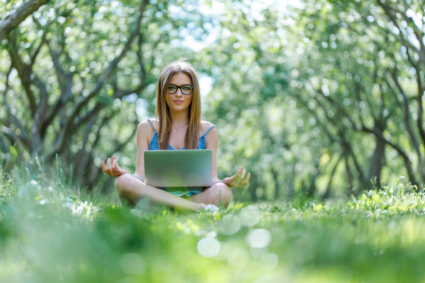 Studentin sitzt mit Laptop in Lotusposition im Park - Foto, Bild