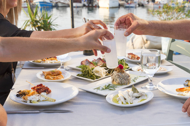 Personas comiendo diferentes comidas de mariscos y bebiendo en la cafetería al aire libre
  - Foto, Imagen