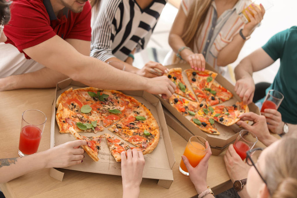 Young people eating delicious pizzas at table, closeup - Fotó, kép