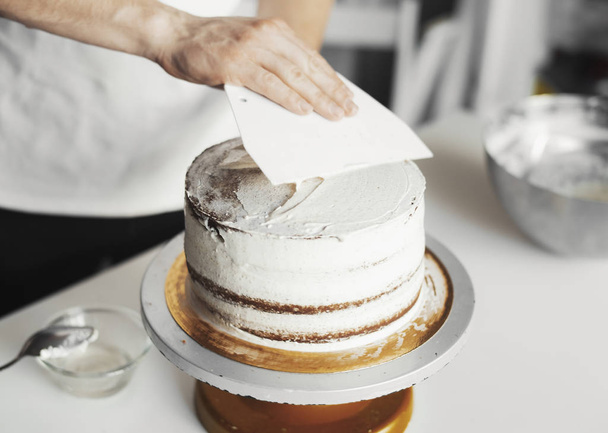 Close up of cook smearing butter cream on chocolate cake. - Fotoğraf, Görsel
