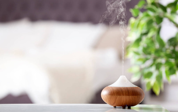 Aroma oil diffuser lamp on table against blurred background - Fotoğraf, Görsel