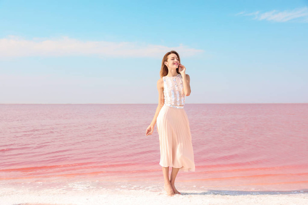 Beautiful woman posing near pink lake on sunny day - Foto, Imagen