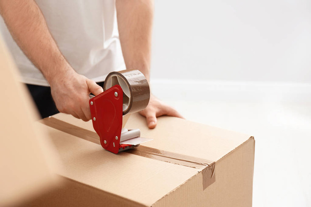 Man packing carton box indoors, closeup. Moving day - Fotó, kép