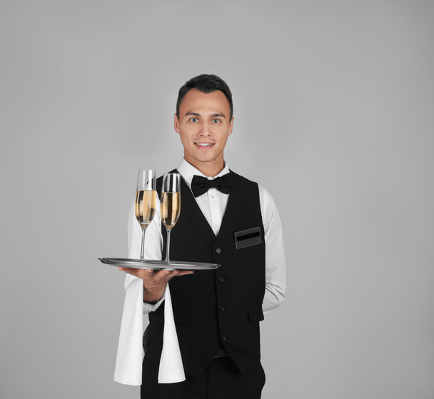 Waiter holding metal tray with lid on grey background - Foto, immagini