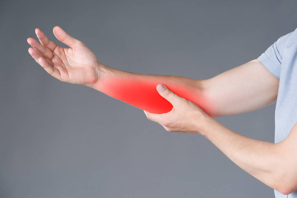 Pain in forearm, muscle inflammation, studio shot on gray background, painful area highlighted in red - Foto, imagen