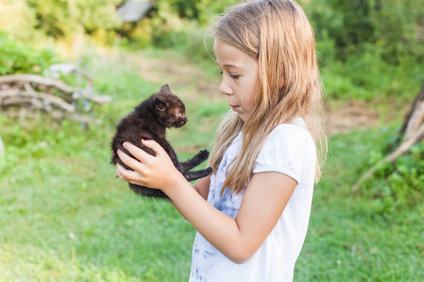 Щаслива чарівна маленька дівчинка з її домашньою кошеняткою на відкритому повітрі влітку
  - Фото, зображення