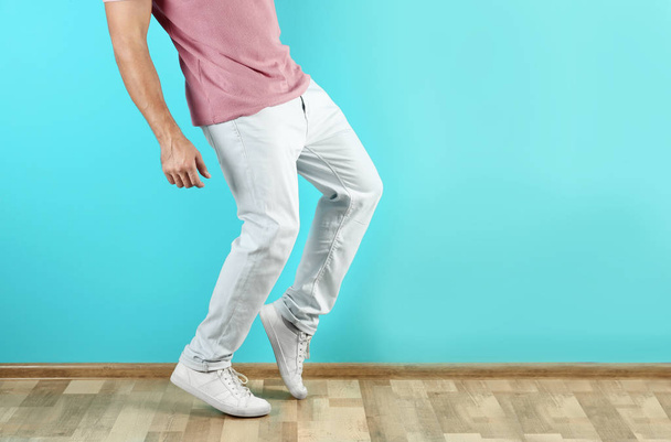 Young man in stylish jeans near color wall, focus on legs - Foto, Imagen