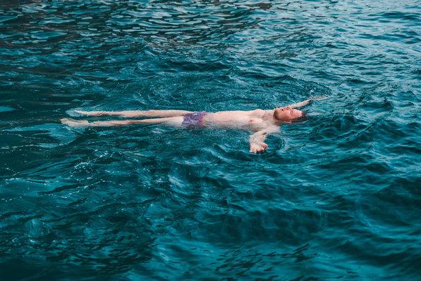 man swimming on back in blue transparent sea water. summer vacation - Photo, Image