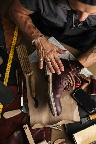 Close up of shoe maker hands producing boots in his leather workshop - Fotografie, Obrázek