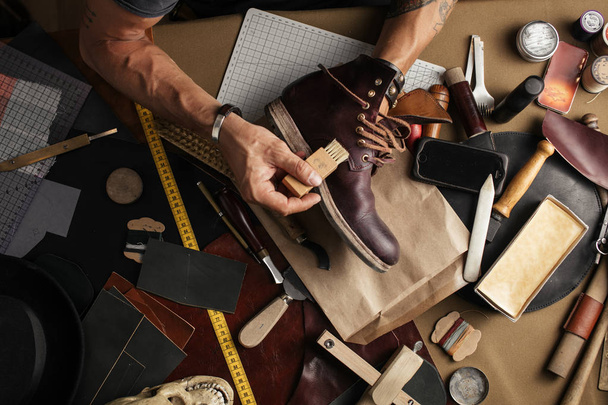 Close up of shoe maker hands producing boots in his leather workshop - Photo, Image