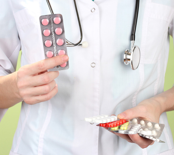 Close-up van vrouwelijke arts hand met pillen, op een achtergrond met kleur - Foto, afbeelding