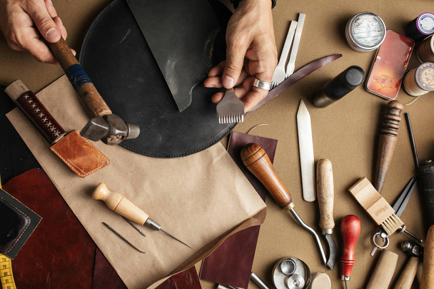 Close up of skinner craftsman working with natural leather using craft tools. - Foto, Imagen