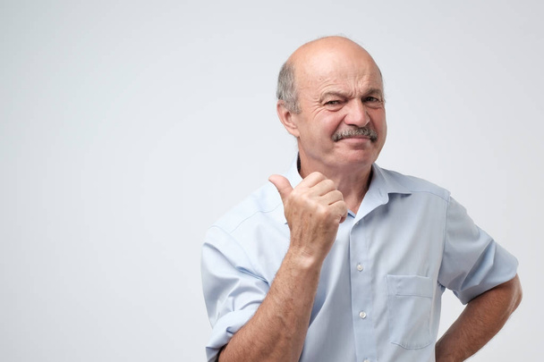 Senior vonzó férfi megoldottad, mint ő eszik valami savanyú és mutatja a hüvelykujj fel. - Fotó, kép
