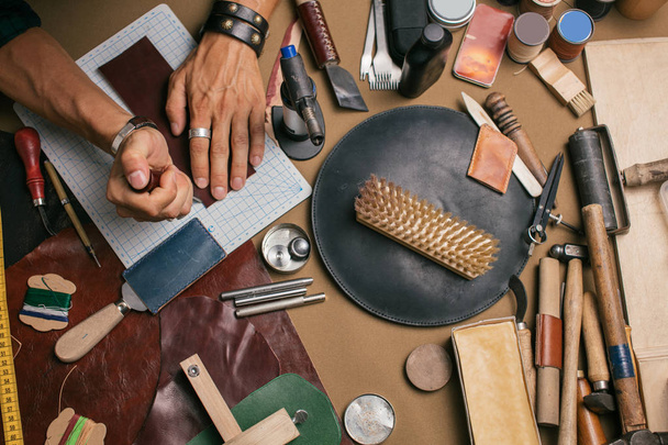 Close up of a shoemaker working with leather textile and hammer at a workshop - Photo, image