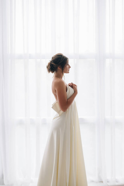 Жінка біле плаття манекенниця у довгі шовкові сукні, розмахуючи Flying тканини, майоріли на вітер - Фото, зображення