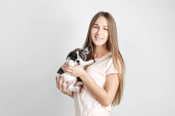 Güzel bir genç kız bir Fransız bulldog yavru tutuyor. - Fotoğraf, Görsel