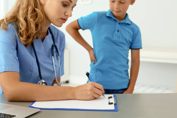 Female medical assistant consulting child in clinic - Foto, Bild