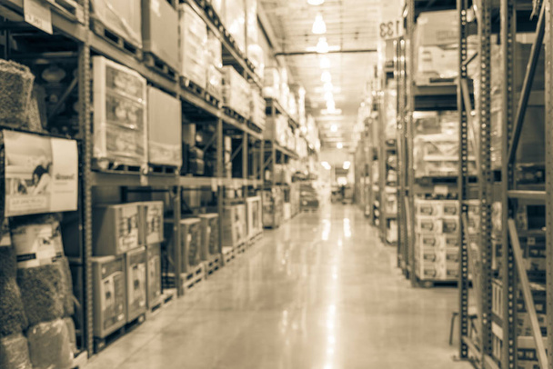 Vintage tone blurred image large warehouse with row of aisles and shelves from floor to ceiling with bin number. Defocused background of industrial distribution storehouse interior wholesale - Photo, Image