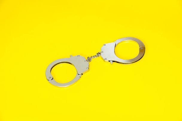 Metal handcuffs isolated on yellow background - Foto, Imagem