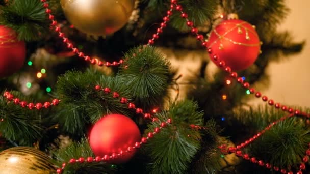 Nahaufnahme 4k Video von bunten Lichtern und Kugeln, die am Weihnachtsbaum im Wohnzimmer hängen. perfektes Filmmaterial für den Winterurlaub - Filmmaterial, Video