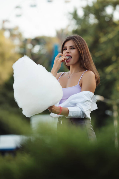 Happy woman eating cotton candy in a park - Fotó, kép