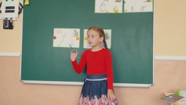 the girl is standing near the blackboard - Imágenes, Vídeo