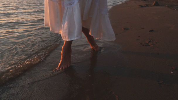 Gyönyörű csupasz láb a tengerparton. Tengeri hab mosás, női lábak. Kép a homok a parton hullám méter. Napsütés, az óceán, hullám. Nyári üdülés tenger hullámai és a homok. lassú - Felvétel, videó