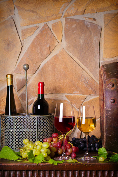 Червоно-біле вино з виноградом поруч зі старою кошиком у винному підвалі. Окуляри та пляшки вина
 - Фото, зображення