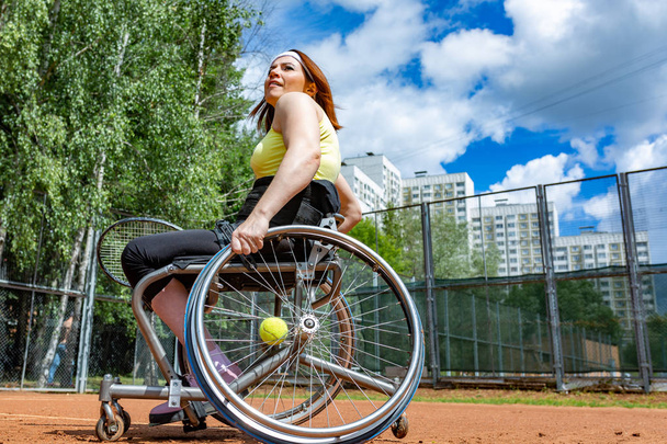 Joven discapacitada en silla de ruedas jugando tenis en pista de tenis
. - Foto, Imagen