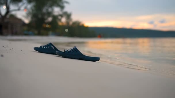 Flip flops lies on the beach with the sunset at the background.  - Footage, Video
