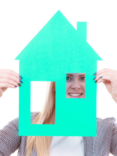 Unelmoi vakaudesta ja perheestä. Blondi tyttö pitelee vihreää paperia talon malli katkaisu. Uusi asunto. Eristetty valkoisella
 - Valokuva, kuva