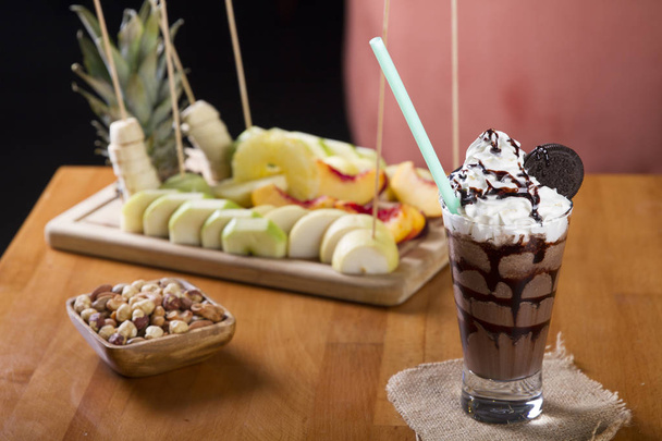 Delicioso batido helado fresco casero que sirve con frutas frescas sobre un fondo rústico de mesa de madera
 - Foto, Imagen