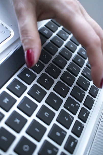 Secretario mecanógrafo escribiendo en el ordenador portátil pc teclas de teclado con las manos con esmalte de uñas rojo
. - Foto, Imagen