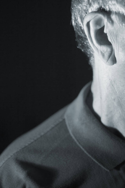Deaf senior citizen man wearing modern digital high technology hearing aid in ear. - Fotoğraf, Görsel