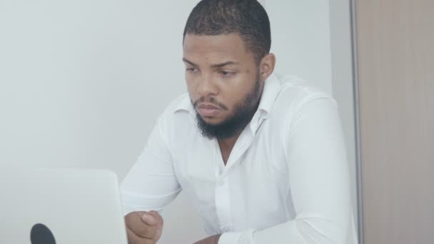 Vakava musta mies työskentelee käyttää tietokonetta etsii näytön toimistossa. Afrikkalainen amerikkalainen liikemies worling kannettavan
. - Materiaali, video